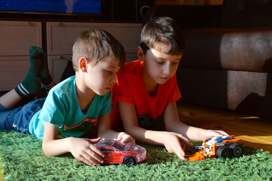 Niños jugando con vehículos de juguete en casa