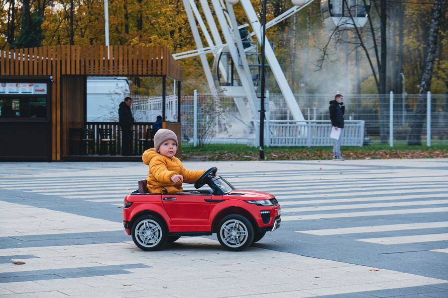 Niño en coche de juguete en calle segura